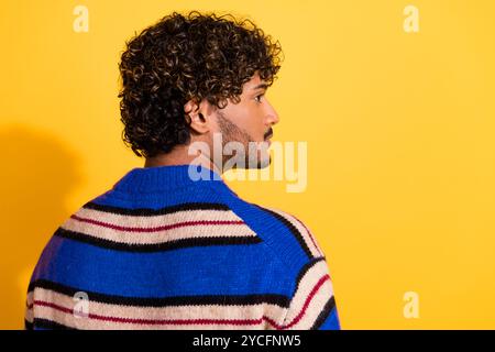 Foto-Porträt des attraktiven jungen Mannes Rückansicht Blick leerer Raum gekleidet stilvolle blau gestreifte Kleidung isoliert auf gelbem Farbhintergrund Stockfoto