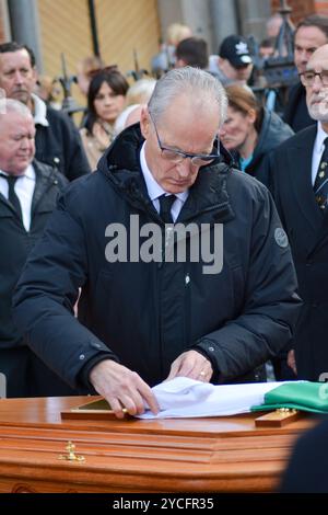 Belfast, Vereinigtes Königreich 23/10/2024 MLA Gerry Kelly faltet einen irischen Dreikolor auf dem Sarg von Roy Walsh. Trauerprozession von Roy Walsh. Roy Walsh diente als Freiwilliger für die Provisorische IRA und wurde für seine Beteiligung am Bombenanschlag von Old Bailey in Belfast Northern Ireland im Jahr 1973 verurteilt Credit:HeadlineX/Alamy Live News Stockfoto