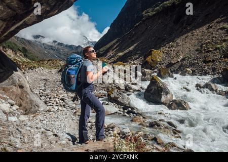 Junge Wanderer Backpacker weiblich am Klippenrand und genießen die Kraft des Gebirgsflusses während der Akklimatisierungswanderung in großer Höhe. Makalu Barun Nationalpark Tre Stockfoto