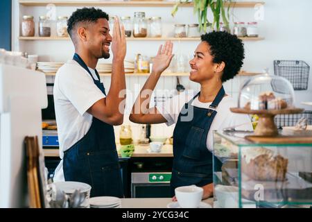Bäckerei, fröhliches Porträt von hispanischen schwarzen Männern und Frauen im Café, bereit für Gebäck, Kaffee und gebackene Speisen - selbstbewusster Kellner Barista an der Theke Stockfoto