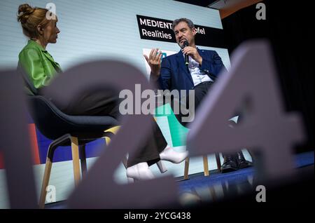 München, Deutschland. Oktober 2024. Die Journalistin Eva Schulz und Markus Söder (CSU), Ministerpräsident Bayerns, sitzen zu Beginn der 38. Medientage München zusammen auf der Bühne. Die Medientage finden bis zum 25. Oktober 2024 in der bayerischen Landeshauptstadt statt. Quelle: Peter Kneffel/dpa/Alamy Live News Stockfoto