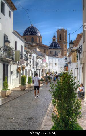 Blick auf eine traditionelle spanische enge Straße mit der Kirche in der Ferne in der Stadt Altea in der Provinz Alicante Spanien Stockfoto