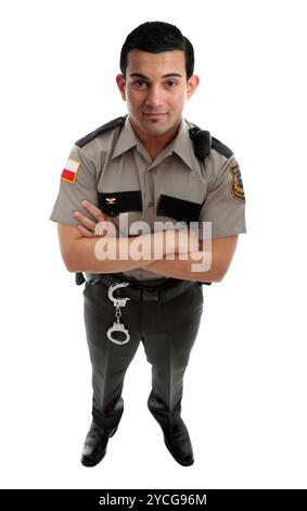 Ein männlicher Gefängniswärter oder Polizist in Uniform mit Gürtel und Funkgerät. Stehen mit gekreuzten Armen und schauen nach oben. Weißer Hintergrund Stockfoto