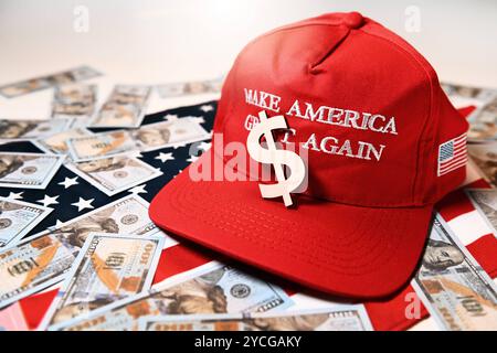 Wahlkampfmütze von Donald Trump mit Aufschrift Make America Great Again auf USA-Fahne mit Dollars und Dollarzeichen, Symbolfoto US-Präsidentschaftswahlkampf *** Wahlkampfmütze von Donald Trump mit Aufschrift Make America Great Again auf US-Flagge mit Dollars und Dollarzeichen, symbolisches Foto US-Präsidentschaftswahlkampf Stockfoto