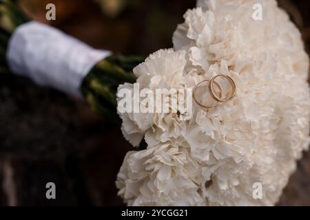 Eleganter Hochzeitsstrauß mit goldenen Ringen auf weißen Nelken. Stockfoto