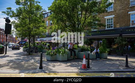 London - 06 15 2022: Menschen in der Mittagspause sitzen im Garten auf Orange Square Stockfoto