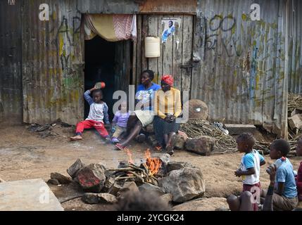 KIBERA SLUM IN NAIROBI, KENIA - 18. NOVEMBER 2022: Slumbewohner sitzen vor ihren armen Hütten in Kibera. Kenia, Afrika Stockfoto