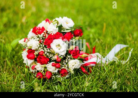 Leuchtender Blumenstrauß mit roten und weißen Rosen vor einem üppigen grünen Hintergrund. Stockfoto