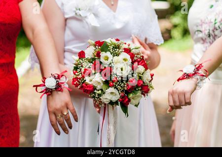 Eleganter Brautstrauß umgeben von fröhlichen Brautjungfern in einer üppigen Umgebung im Freien. Stockfoto