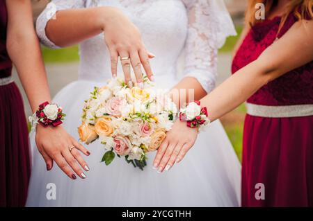 Eleganter Brautstrauß umgeben von fröhlichen Brautjungfern in wunderschöner Kleidung. Stockfoto