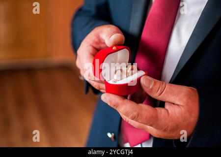 Elegante Präsentation von Hochzeitsringen in einer luxuriösen roten Samtbox. Stockfoto