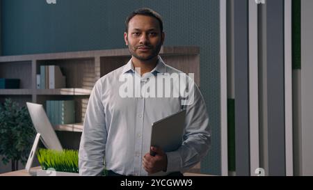 Geschäftsporträt im Büro Erwachsener indischer Mann amerikanischer Mann ethnischer Geschäftsmann Unternehmer Arbeitgeber mit Laptop posiert am Arbeitsplatz modernes Marketing Stockfoto