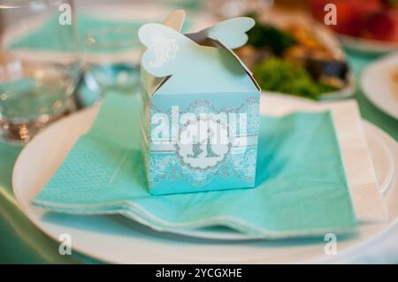 Elegante Favor Box im Aqua-Stil mit zartem Schmetterlingsdetail auf festlichem Tisch. Stockfoto