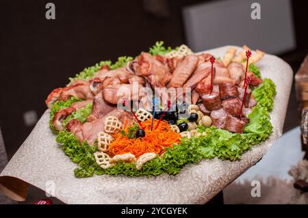 Exquisite Charcuterie-Platte, umgeben von frischen Grüns. Stockfoto
