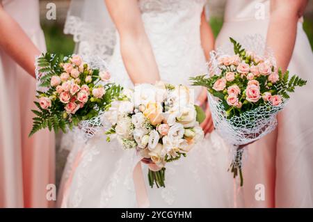 Eleganter Brautstrauß umgeben von Blumenarrangements der Brautjungfern in sanften Pastelltönen. Stockfoto