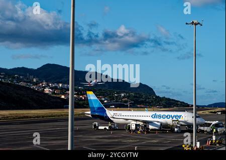 Ein Flugzeug startet, da ein anderes Flugzeug von Discover Airlines für den Einstieg am Flughafen Funchal vorbereitet ist Stockfoto