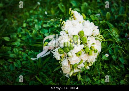 Ein wunderschön gestalteter weißer Blumenstrauß, eingebettet in üppiges grünes Gras. Stockfoto