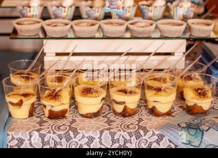 Exquisite Präsentation von mehrschichtigen Desserts in eleganten Glastassen mit dekorativem Hintergrund. Stockfoto