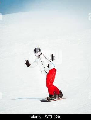 Vorderansicht junger cooler Mann Snowboarden auf den Pisten des Skigebietes isoliert am verschneiten Tag Stockfoto