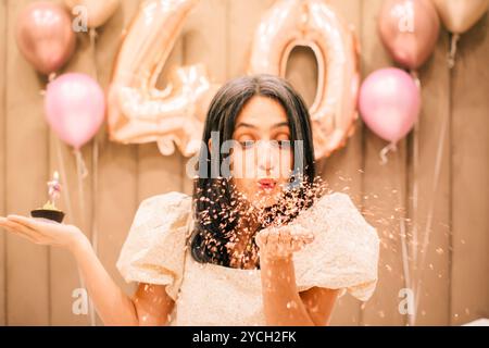 Nahaufnahme ziemlich reife natürliche aussehende glückliche schlanke kaukasische Frau feiern Geburtstagsparty Blase Blase Cupcake Kerze Stockfoto