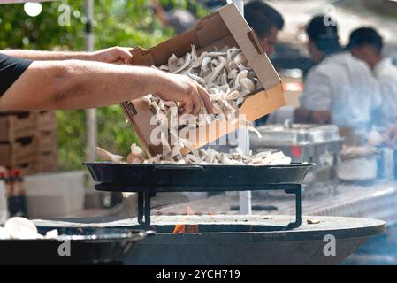 Koch bereitet vegetarische Gerichte beim Outdoor Food Festival zu, indem er frische Austernpilze grillt Stockfoto