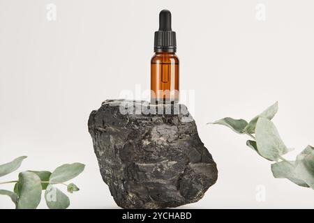 Serum, Massageöl in Glastropfflasche auf Basalt. Stockfoto