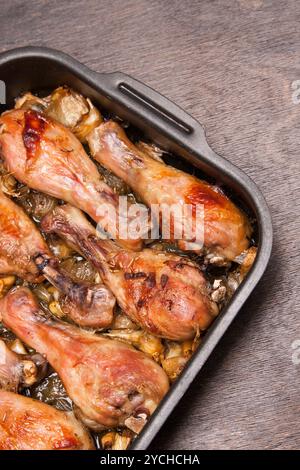 Gebackene Hähnchenschenkel in Tablett auf schwarzem Holz Stockfoto