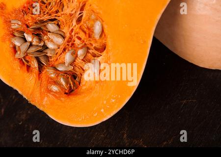 Halber frischer Orangenkürbis auf schwarzem Holz Stockfoto