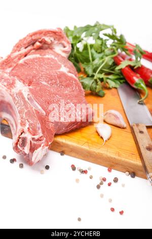 Frisches Rindfleisch mit Knochen auf hölzernen Gewürzen und Messer Stockfoto