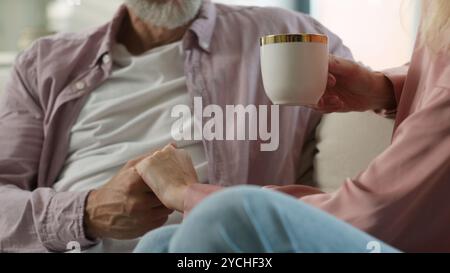 Liebevoll liebevoll liebevoll älterer kaukasischer Mann Mann Kuss Hand geliebte Frau Frau trinkt aromatischen Kaffee genießt zärtlichen romantischen Liebesmoment Stockfoto