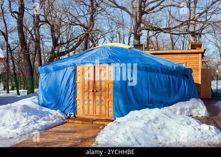 Eine blaue Jurte mit großer geschlossener orangener Tür im Winterpark Stockfoto