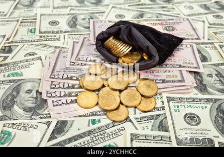 Tasche voller Münzen über US-Banknoten Hintergrund Stockfoto