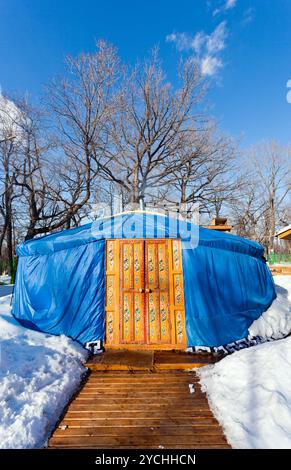 Eine blaue Jurte mit großer geschlossener orangener Tür im Winterpark Stockfoto