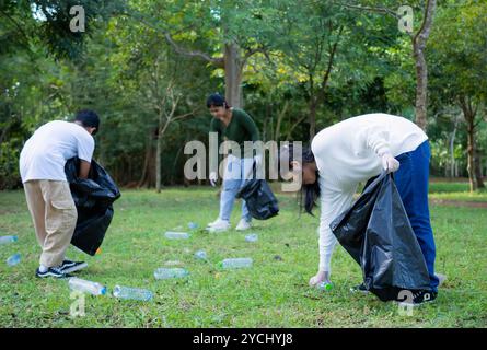 Eine Gruppe engagierter junger Freiwilliger nimmt an einer Umweltreinigung in einem Park Teil. Freiwillige halten große schwarze Taschen in der Hand. Personen A Stockfoto