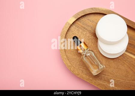 Wattepads mit Kosmetiköl auf rosa Hintergrund. Draufsicht Stockfoto