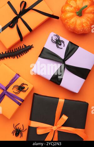 Happy Halloween Holiday Konzept. Flache Geschenkboxen, orangefarbene Kürbisse, Fledermäuse, Spinnen auf orangem Hintergrund. Halloween Grußkarte Vorlage. Draufsicht Stockfoto