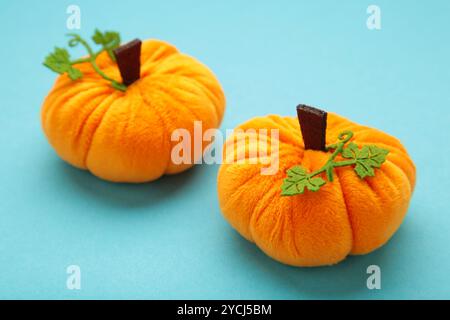 Halloween Dekoration Spielzeug Plüschkürbisse mit einem grünen Blatt auf blauem Hintergrund. Draufsicht Stockfoto