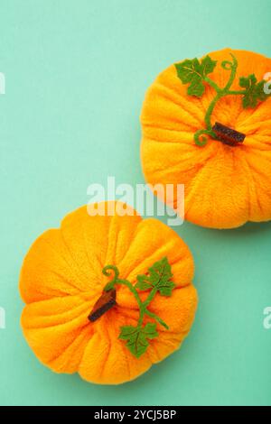 Halloween Dekoration Spielzeug Plüschkürbisse mit einem grünen Blatt auf minzfarbenen Hintergrund. Draufsicht Stockfoto