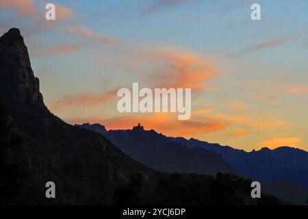 Sonnenuntergang über den fernen Bergen mit einem Teil des Watchman, einem der berühmten Gipfel des Zion-Nationalparks im Vordergrund Stockfoto