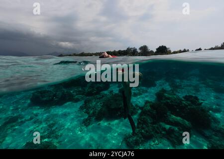 Junge Frau in rotem Bikinizone, die in Maske und Tube im Meer in der Nähe der Küste schnorchelt Stockfoto