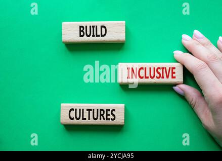 Symbol „integrative Kulturen erstellen“. Holzblöcke mit Wörtern bilden inklusiv-Kulturen. Schöner grüner Hintergrund. Geschäftsmann Hand. Business und Build I Stockfoto
