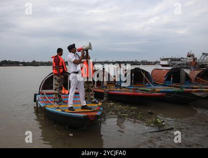 Zyklon-Dana-Alarm in Kalkutta, Indien Ein Mitglied der Verkehrspolizei auf dem Fluss Kalkutta appelliert mit einem Megaphon an die Menschen, an einen sichereren Ort vor Zyklon Dana zu ziehen, während einer Patrouille auf dem Fluss Ganges in Kalkutta, Indien, am 23. Oktober 2024. Das Regional Meteorological Centre Kolkata IMD hat prognostiziert, dass der Zyklon Dana in den nächsten drei Tagen starke Regenfälle in verschiedenen Bezirken in Odischa und Westbengalen bringen wird. Der Wirbelsturm soll am 25. Oktober zwischen dem Bhitarkanika-Nationalpark und dem Hafen von Dhamra in Odisha an Land kommen, wobei die Windgeschwindigkeiten bis zu 120 Kilometer betragen können Stockfoto