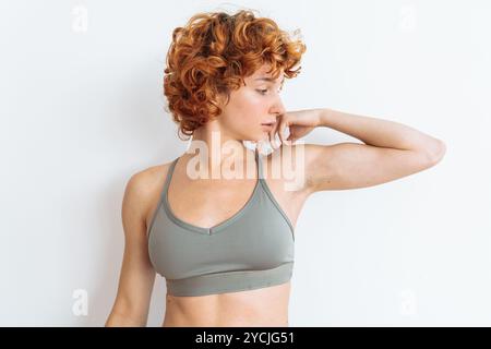 Porträt einer jungen Frau mit sportlichem Aufbau, die ein Sporttop trägt und ihre muskulösen Arme zeigt Stockfoto