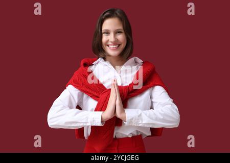 Hübsche junge Frau, die auf rotem Hintergrund meditiert Stockfoto