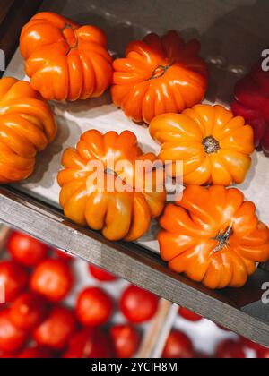 Bunte Tomaten AKKORDEON ORANGE auf der Theke eines Gemüsegeschäfts in Holzkiste, Nahaufnahme Stockfoto