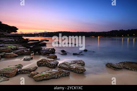 Sonnenaufgang von der Südseite von Rocky Point Island. Die Flut, die über den Felsen an der Küste hineingespült wird. Käufer - Bewegung, lange Belichtung. Stockfoto