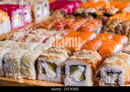 Verschiedene Sushi- und Brötchen auf Holzbrett in dunklem Licht Stockfoto