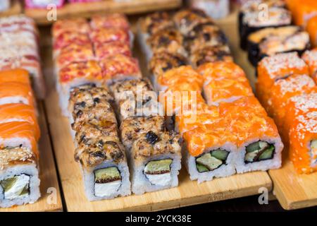 Verschiedene Sushi- und Brötchen auf Holzbrett in dunklem Licht Stockfoto