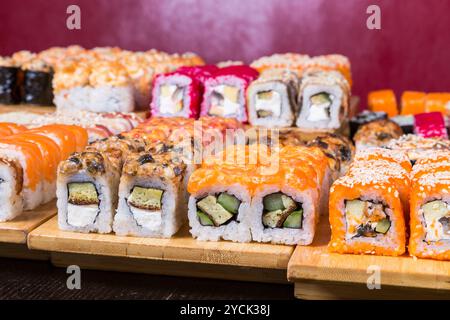 Verschiedene Sushi- und Brötchen auf Holzbrett in dunklem Licht Stockfoto