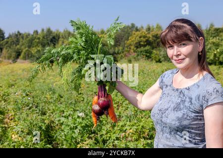 Junge Frau mit Haufen von Gemüse in der hand Stockfoto